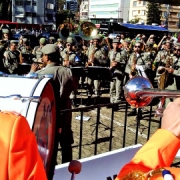 Músicos da Banda da Brigada Militar ao fundo tocando junto de grupo de músicos holandeses com roupas cor de laranja.