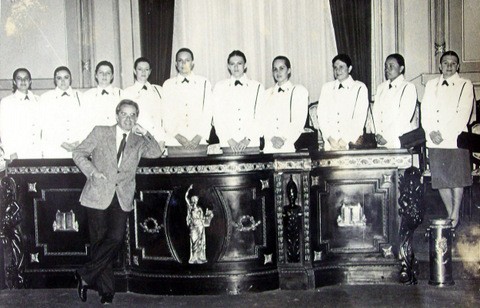 Rui Spohr em frente a alunas da primeira turma de oficiais femininas, que estão atrás de uma bancada, posando para a foto.