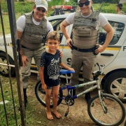 policiais entregando bicicleta a uma criança