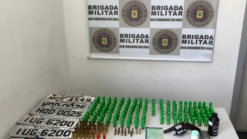 A imagem mostra armas, munições e placas veículares