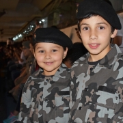 A foto mostra um menino e uma menina fardados