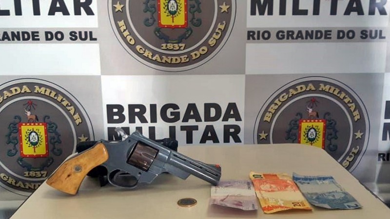 A imagem mostra um revólver e uma quantia em dinheiro