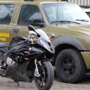 A imagem mostra uma viatura policial e ao lado uma moto BMW