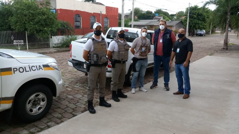 Policiais Militares e agentes municipais do lado de duas viaturas.