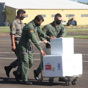 Dois policiais militares levando carrinho de mão com lotes das vacinas para avião