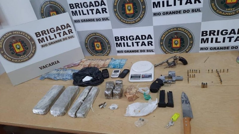 Na foto estão as porções de drogas embaladas, duas armas, munições, uma faca, balança de precisão, três celulares e dinheiro em espécie.