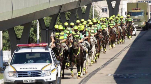 Tropa da cavalaria seguindo uma viatura em uma avenida