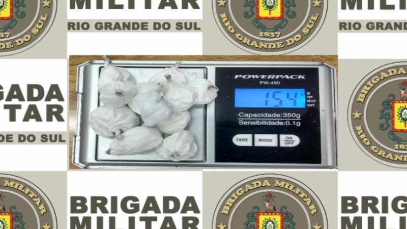 Ao fundo o banner da Brigada Militar. Sobre ele a droga apreendida sobre uma balança de precisão.