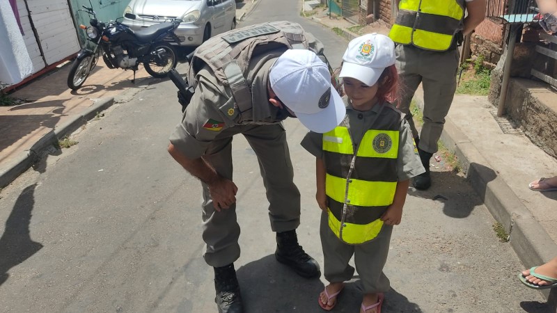Policial Militar agachado conversando com criança