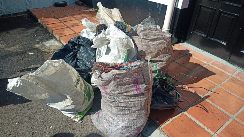 Foto Colorida. No chão, sacos de lona com Fios de Cobre