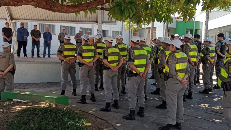 Policiais em forma ouvindo autoridades locais.
