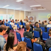 Convidados do evento sentados, assistindo a apresentação do Laboratório.