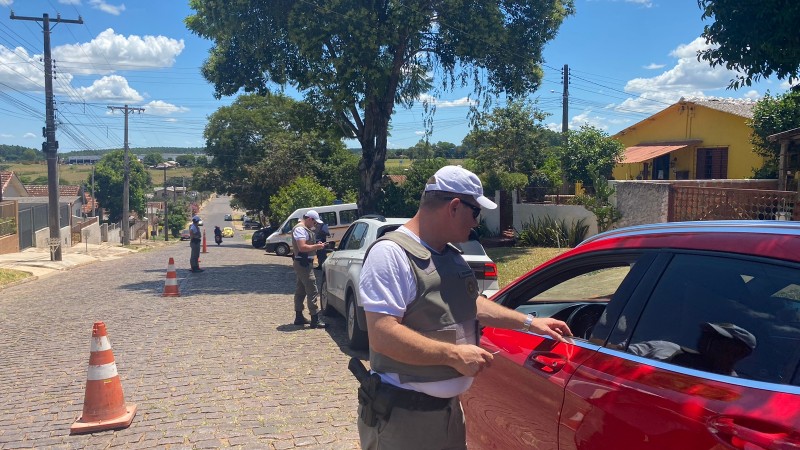 Foto mostra policial conversando com motorista de veículo, durante abordagem em barreira