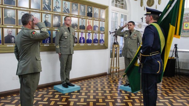Quatro militares estão parados frente a frente em um salão do quartel