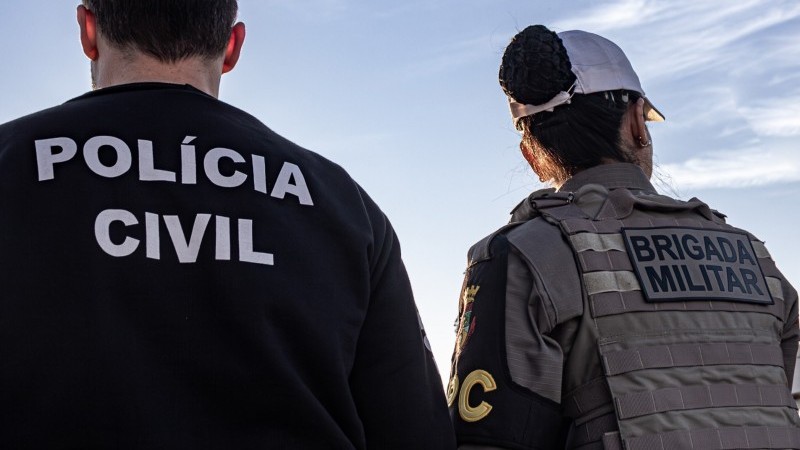 Policial civil e policial militar lado a lado virados de costas para a câmera