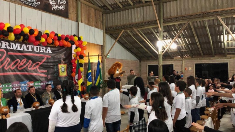 Alunos realizando o juramento junto com instrutores e o mascote Dare