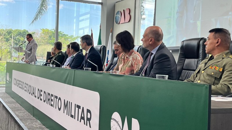 Foto mostra uma mesa com palestrantes em um auditório da OAB