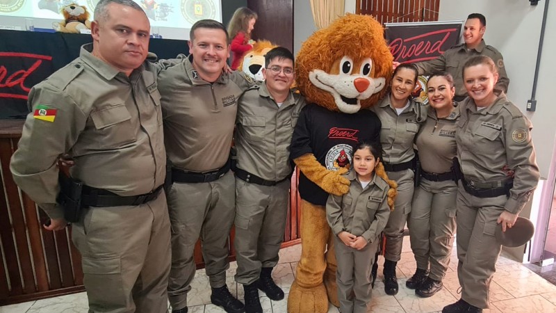 Policiais Militares com o mascote do proerd o Leão DARE