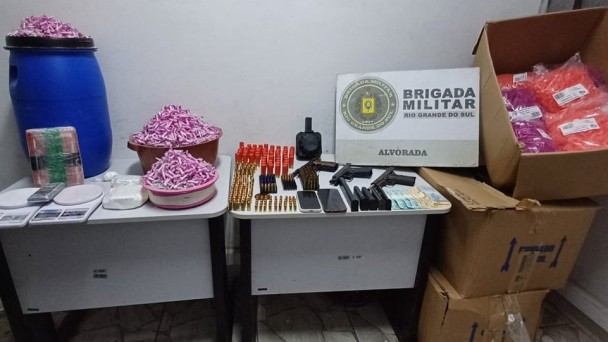Foto mostra armas, drogas e munições em cima de uma mesa.