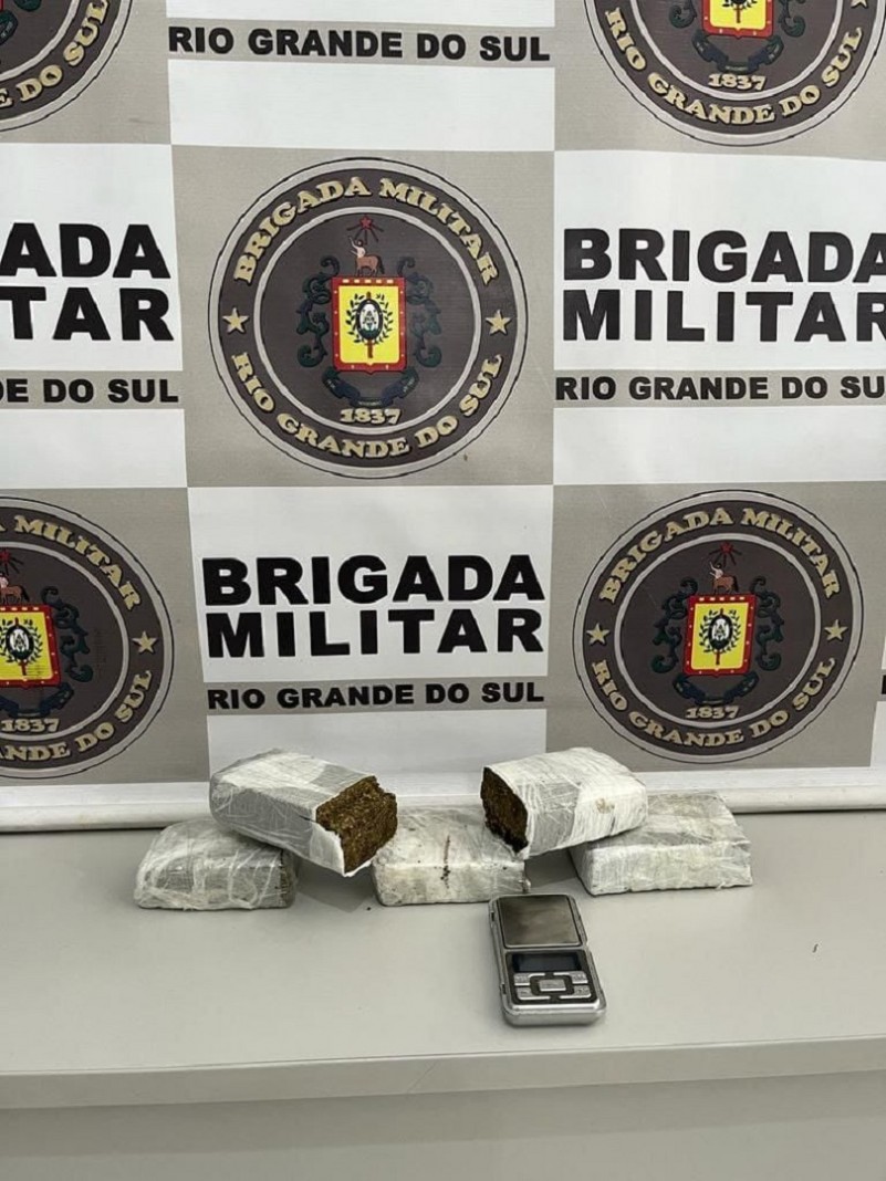 Cinco porções de maconha pesando 1,190kg e uma balança e precisão em cima de um balcão.