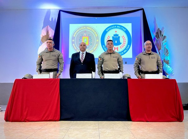Foto da mesa da palestra, com três oficiais da BM e o chefe da Polícia Civil