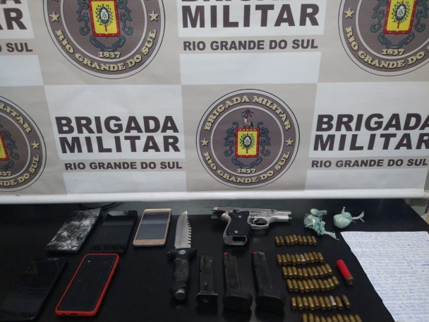 Apreensões sobre uma mesa preta, em frente ao banner da BM.
