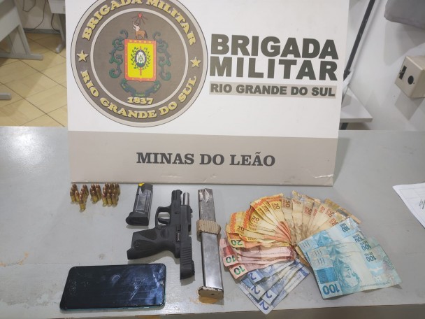 Arma de fogo, munições e dinheiro em frente ao display da BM.
