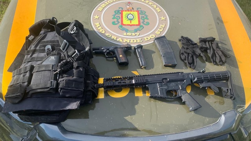Imagem mostra fuzil, pistola, carregadores, munição e colete à prova de balas em cima de um capô de viatura da BM