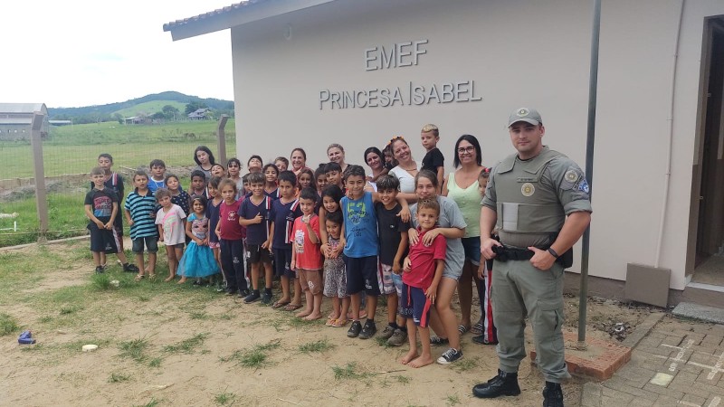 Policial militar junto com alunos de escola de ensino fundamental
