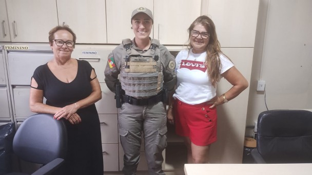 Policial militar feminina juntamente com equipe diretiva em escola de Palmares do Sul