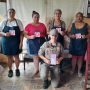 Na foto, encontra-se uma policial militar, integrante da Patrulha Maria da Penha, realizando a entrega de folders para mulheres do comércio.