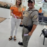 Na foto, um policial militar entrega um folder  para uma mulher do comércio local,  na cidade de Novo Cabrais.