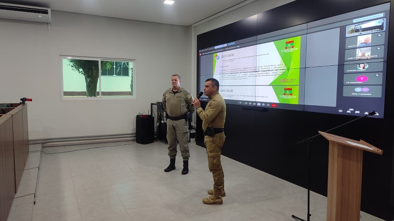 A foto mostra dois oficiais, sendo um da PMSC e outro da BMRS, realizando apresenta&ccedil;&atilde;o em audit&oacute;rio. 