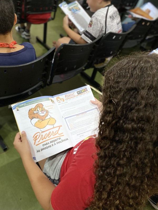Uma menina folhando a cartilha do PROERD