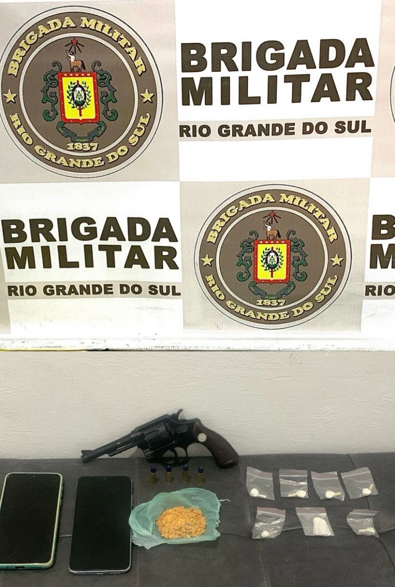 Ao fundo, banner da Brigada Militar e sobre a mesa, diversas porções de crack, sete porções de cocaína e um revólver calibre 32.
