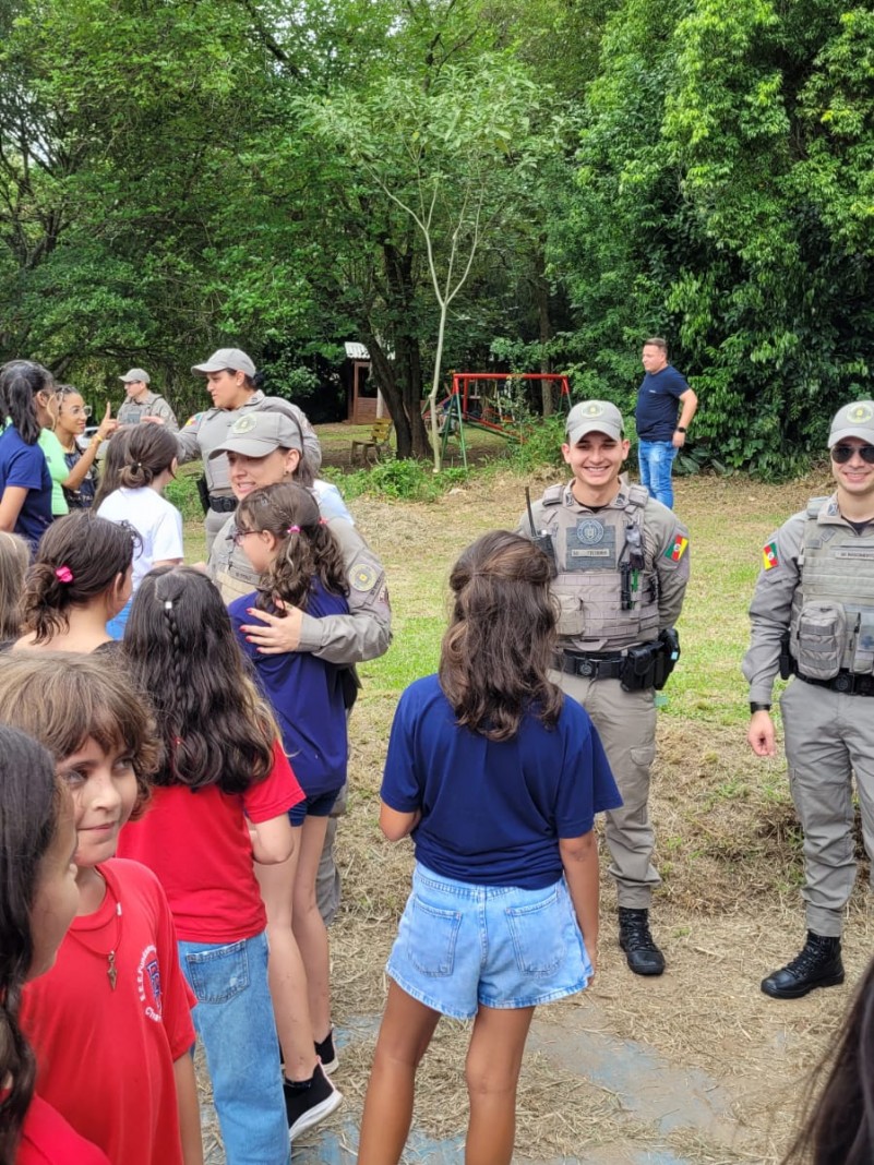 Policiais militares e crianças interagindo no pátio de uma escola
