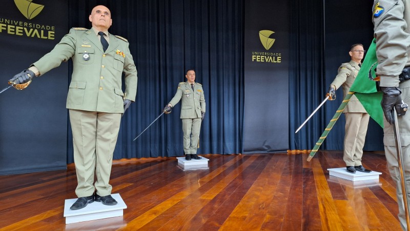 Na imagem, militares empunham espadas em direção à bandeira nacional. 