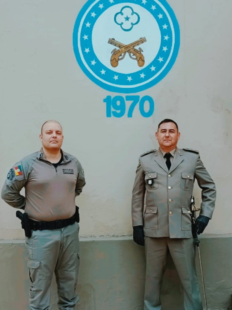 o comandante da escola ao lado do recém chegado tenente weber e ao fundo o símbolo da esfas