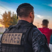 Policial militar das Patrulhas Especiais (Patres) de costas para foto, realizando abordagem durante a operação