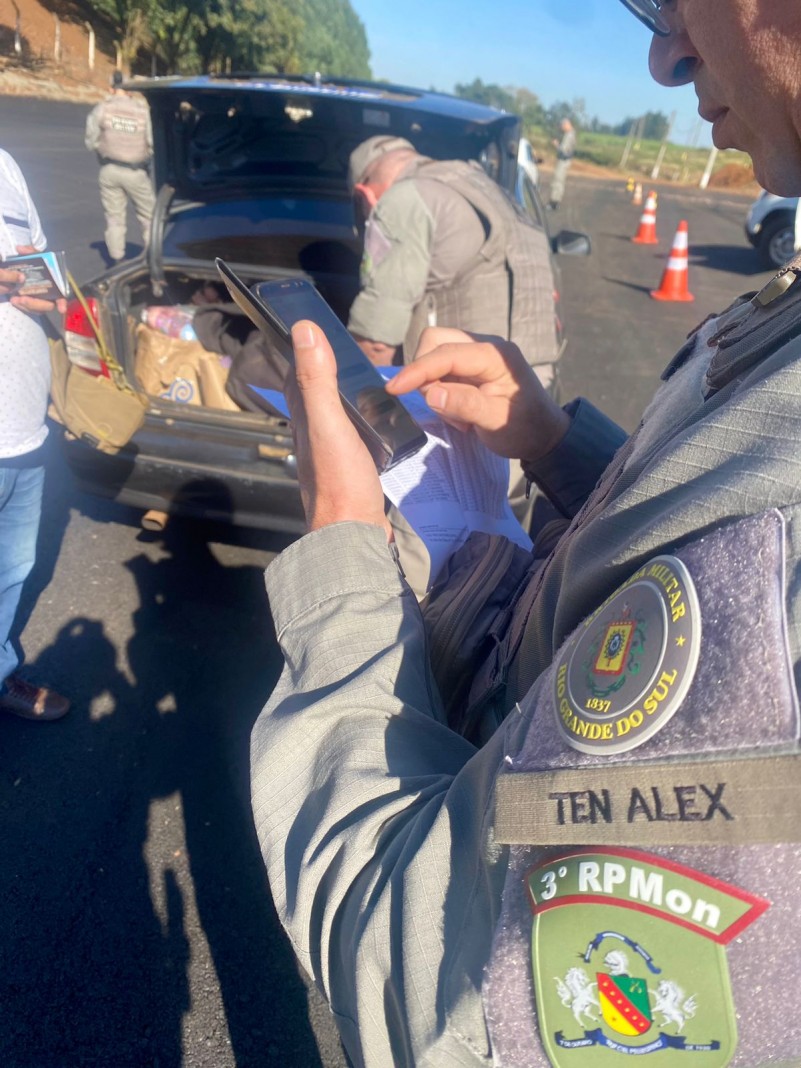 Na foto contém o policial revistando um veículo