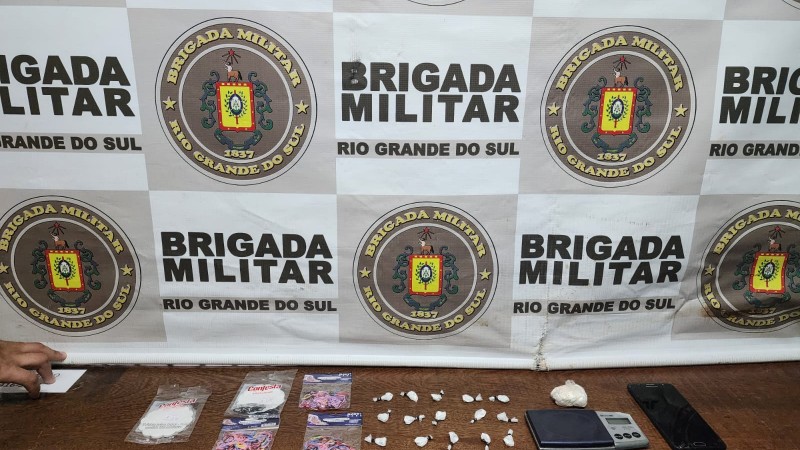 material apreendido em uma mesa, em frente ao banner da BM
