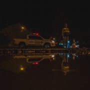 Imagem refletida em água. Viatura e um policial militar no reflexo
