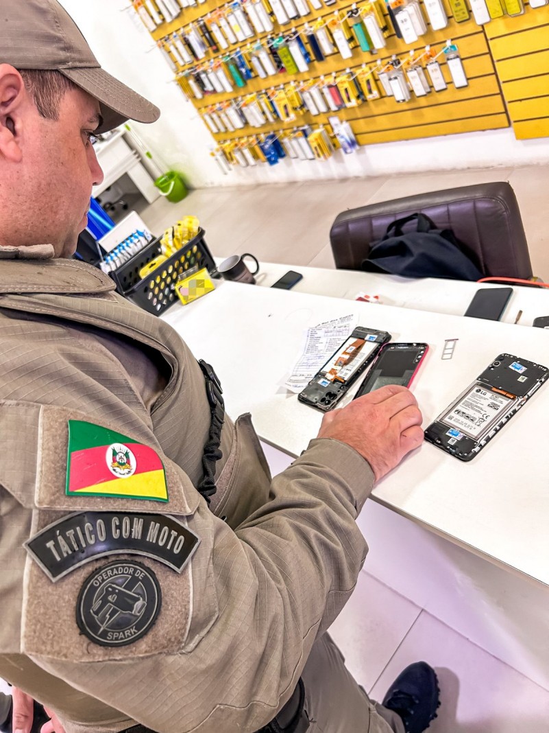 Policial fiscalizando celulares durante operação