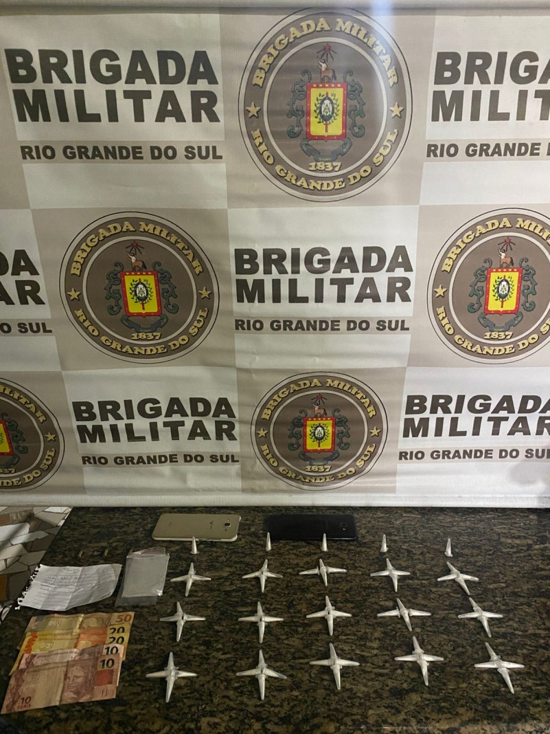 45 pinos de cocaína apreendidos e ao fundo banner da Brigada Militar
