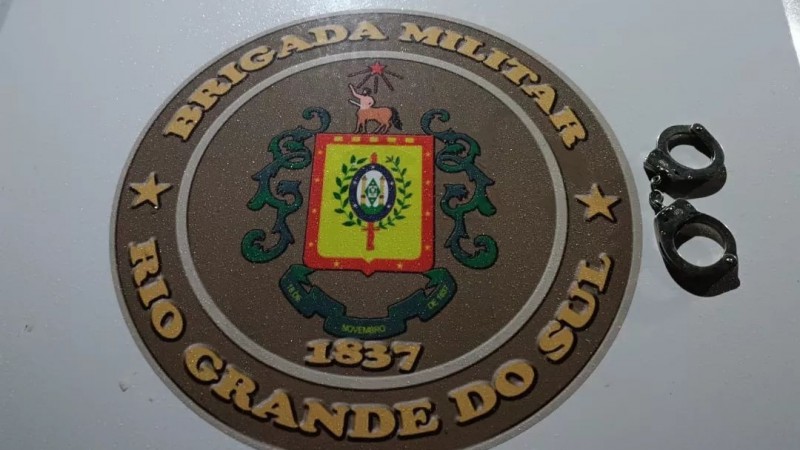 Na imagem, um par de algemas sob o Brasão da Brigada Militar