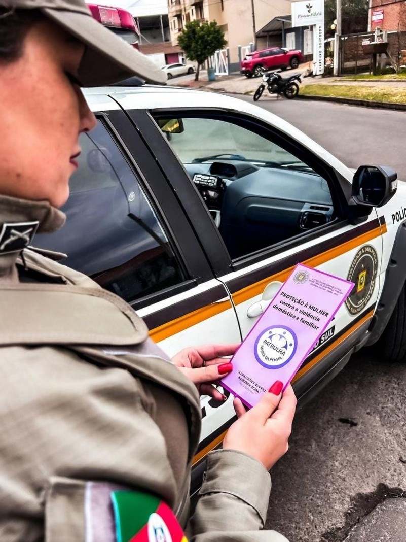 Policial feminina segurando panfleto da Patrulha Maria da Penha