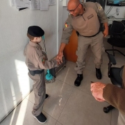 A foto foi tirada dentro do Batalhão da Brigada Militar de Cachoeira do Sul, em uma sala com parede em cor branca e piso em cor bege, nela um policial militar está cumprimentando o pequeno Cassiano, através de um aperto de mão. Ele têm cinco anos e sonha em ser policial.