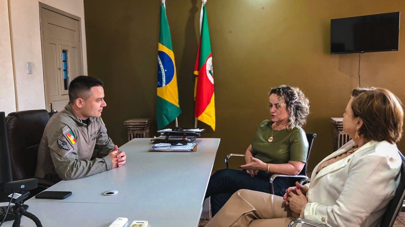 Ao fundo, as bandeiras do Rio Grande do Sul e Brasil. A frente, o capitão e as duas mulheres.