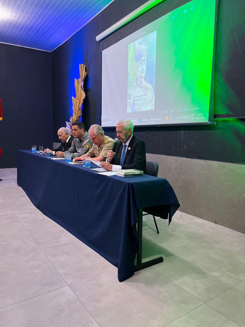 Foto mostra a mesa composta por oficiais em cima de um palco