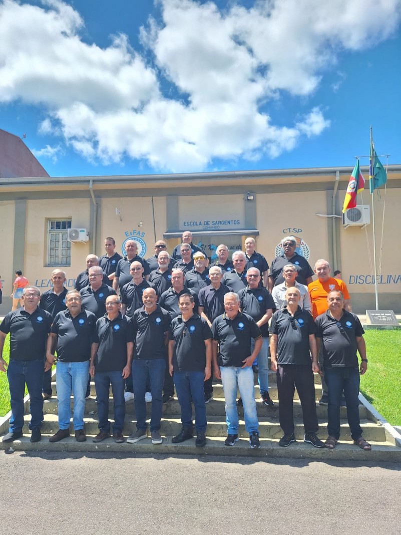turma de veteranos de 1982, postos em uma escadaria e ao fundo a faixada da escola com um lindo céu azul
